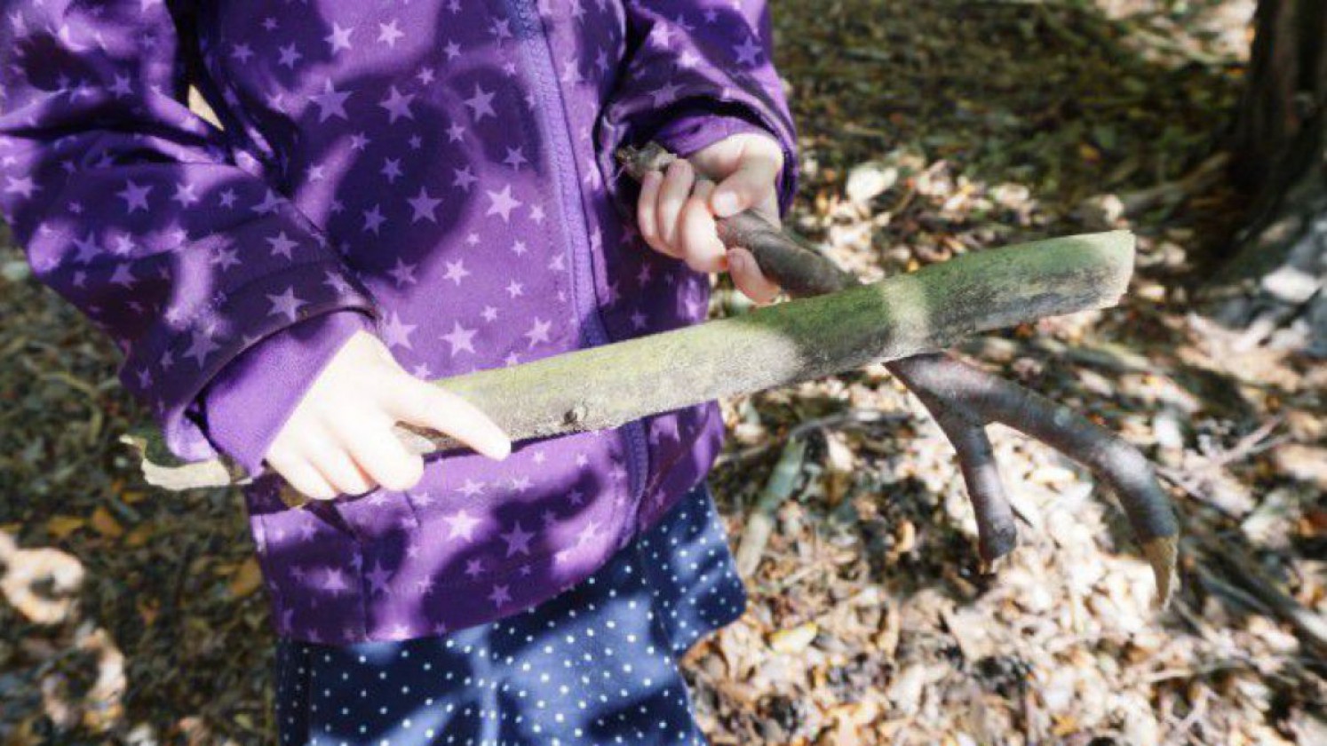 Kind beim Klanghölzer sammeln im Wald.