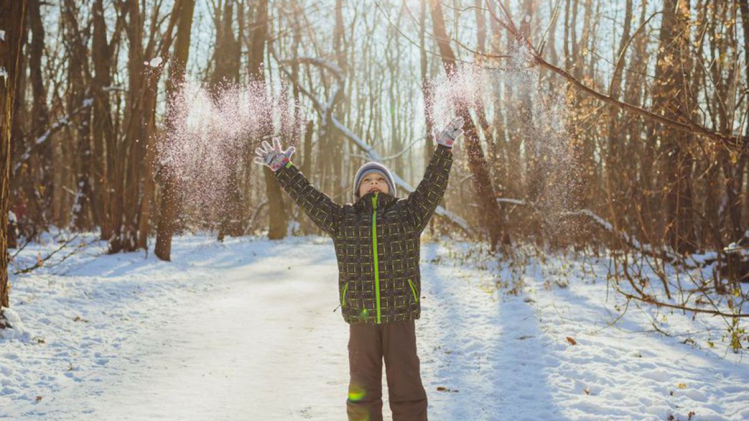 Kind beim Spielen im Winterwald.