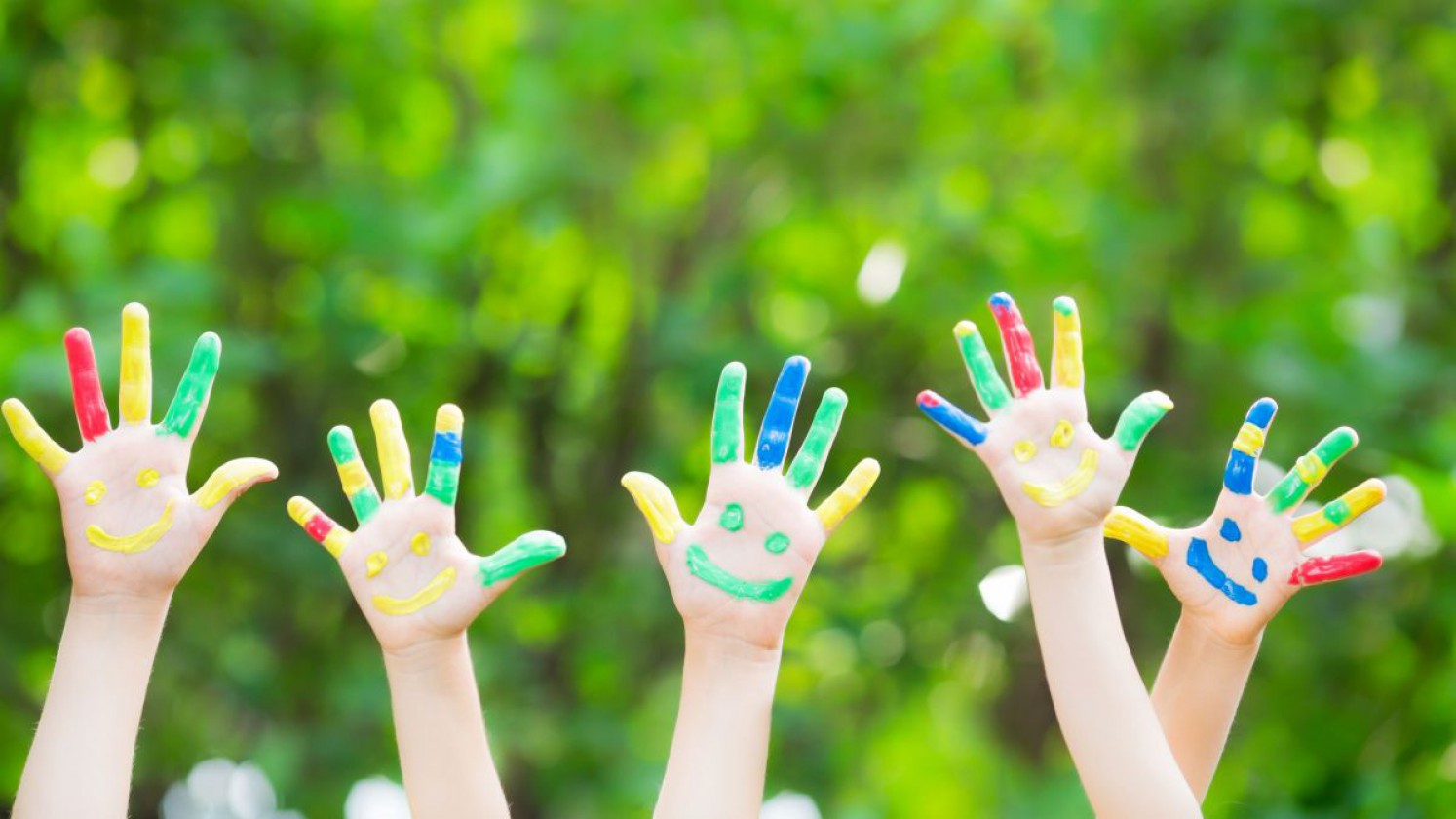 Kinderhände mit bunten Fingerfarben bemalt.