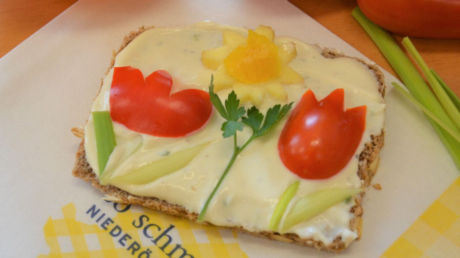 Kreativ dekoriertes Brot mit einer Gemüse-Blumenwiese.