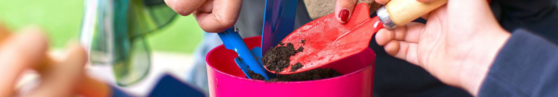 Mehrere Kinder schaufeln Erde in einen Blumentopf