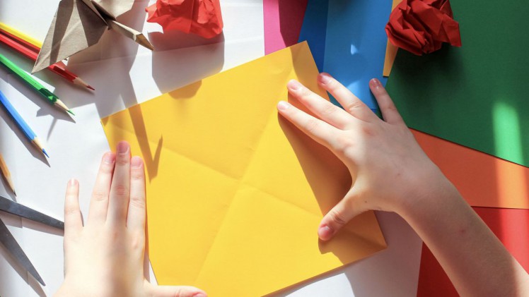 Kind bastelt mit Papier