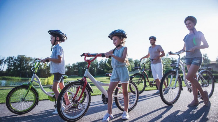Familie macht Ausflug mit Rad, alle tragen Helm