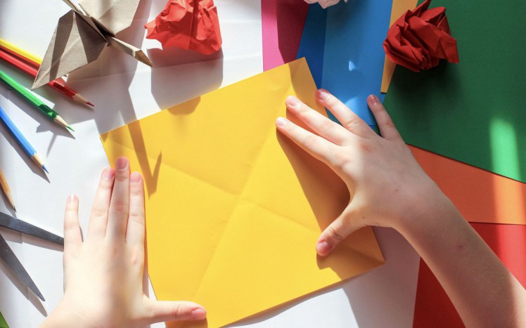 Kind bastelt mit Papier