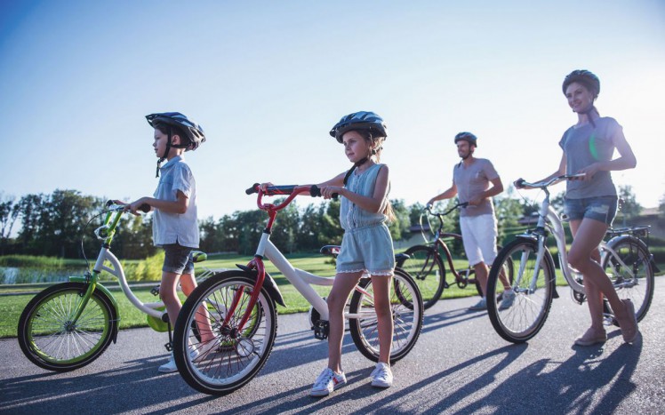 Familie macht Ausflug mit Rad, alle tragen Helm